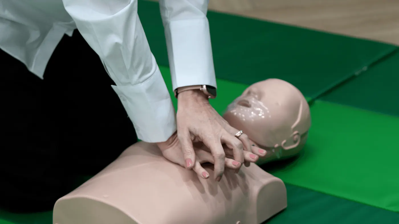 Instructor performing CPR chest compressions on an adult manikin